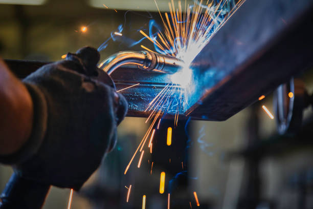 Close-up of MIG welding a steel beam, sparks flying